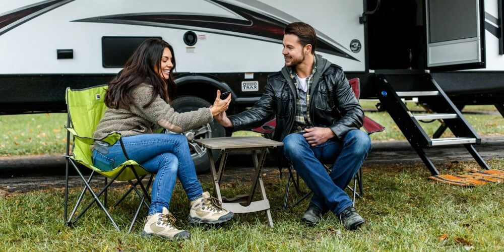 two people sitting in front of an RV taking a selfie