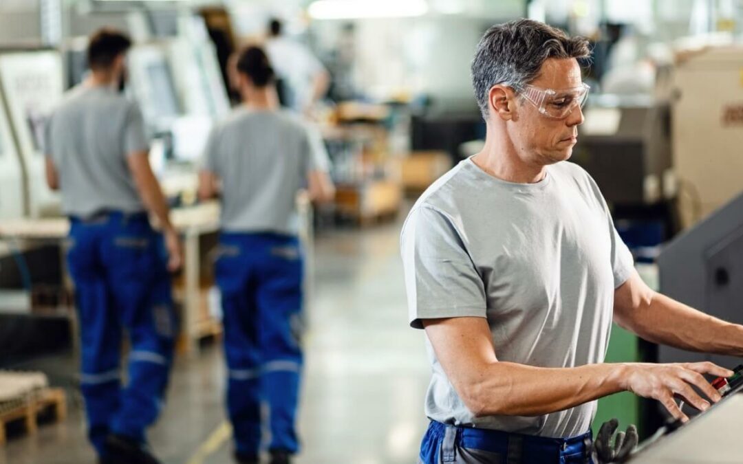 mid adult worker operating cnc machine while working industrial facility