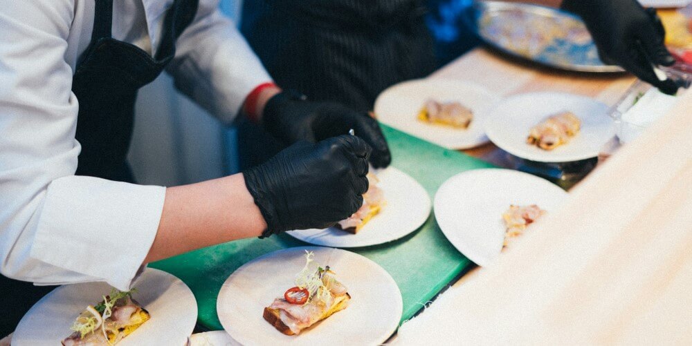 a culinary student wearing food service gloves plates an appetizer